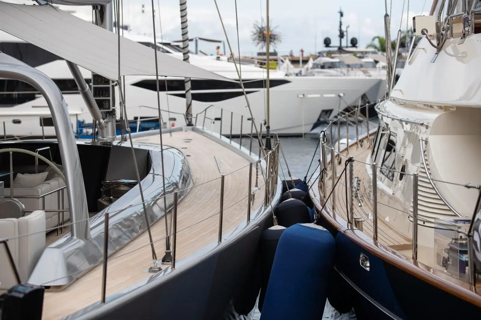 Superyachts moored bow to bow in a European marina, fenders between the hulls